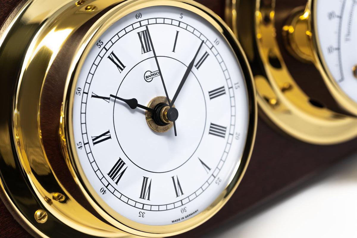 Close-up of a German brass nautical clock with Roman numerals on wooden plaque