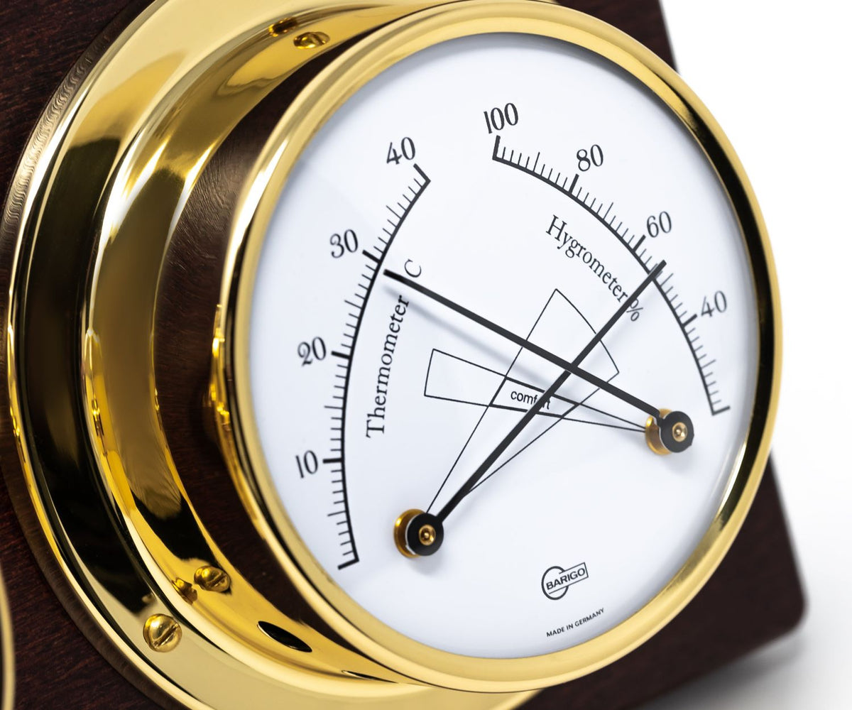 Close-up of a brass analog thermometer and hygrometer on wood, German-made weather instrument
