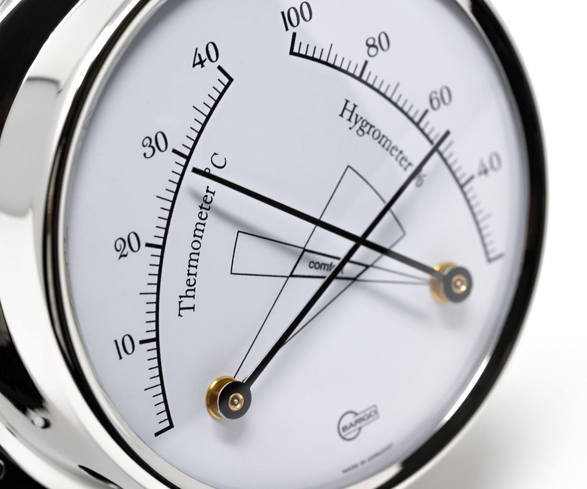 Close-up of analog thermometer and hygrometer in chrome case, measuring temperature and humidity.
