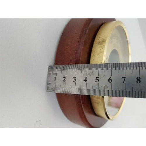 Close-up of brass and wood barometer case with a ruler measuring its diameter