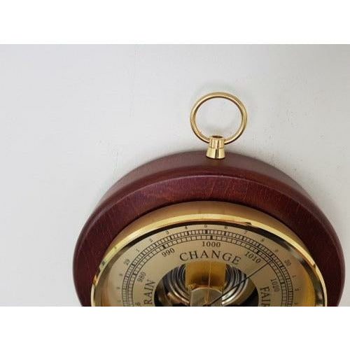 German barometer with brass dial, wooden frame, and wall mount ring for measuring air pressure
