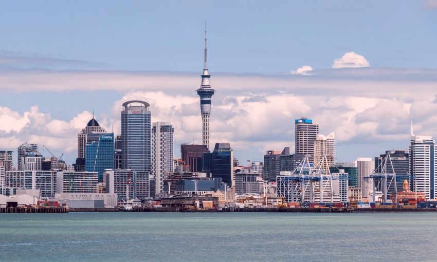 Auckland city skyline with Sky Tower, waterfront, and modern buildings under cloudy sky