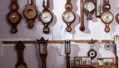 Wall display of antique barometers and clocks with polished wooden frames