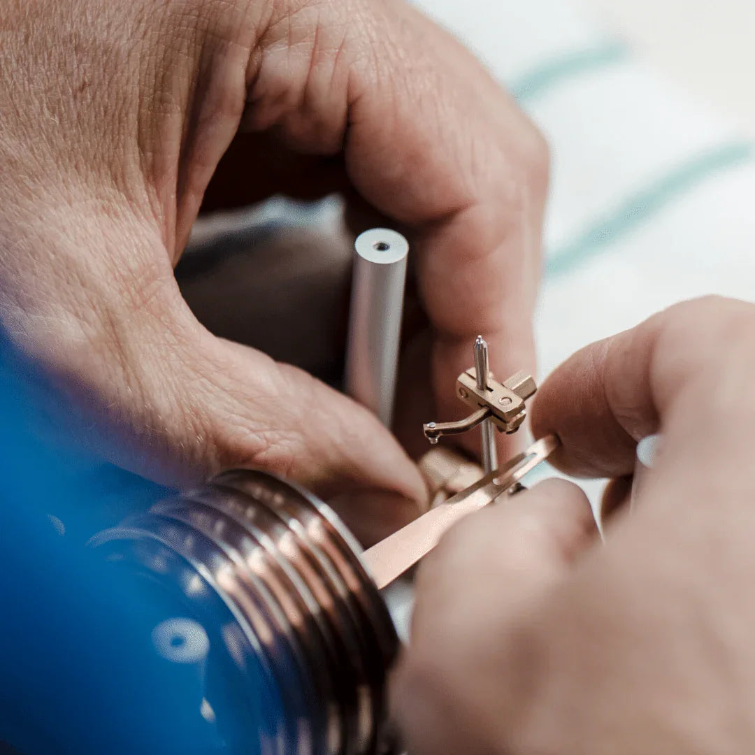 Hands assembling precision barometer or clock component, close-up craftsmanship detail