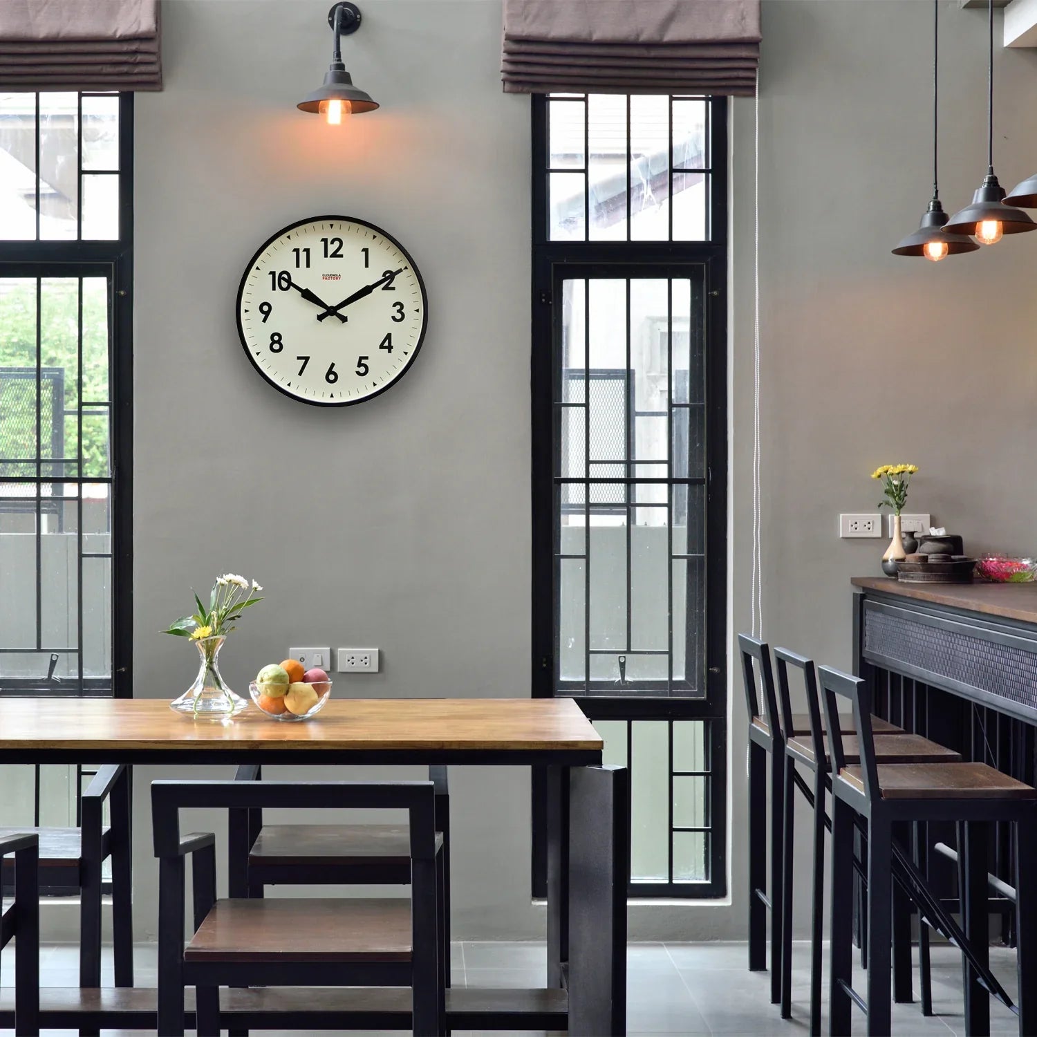 Large wall clock with black frame in modern dining room with wooden table and chairs