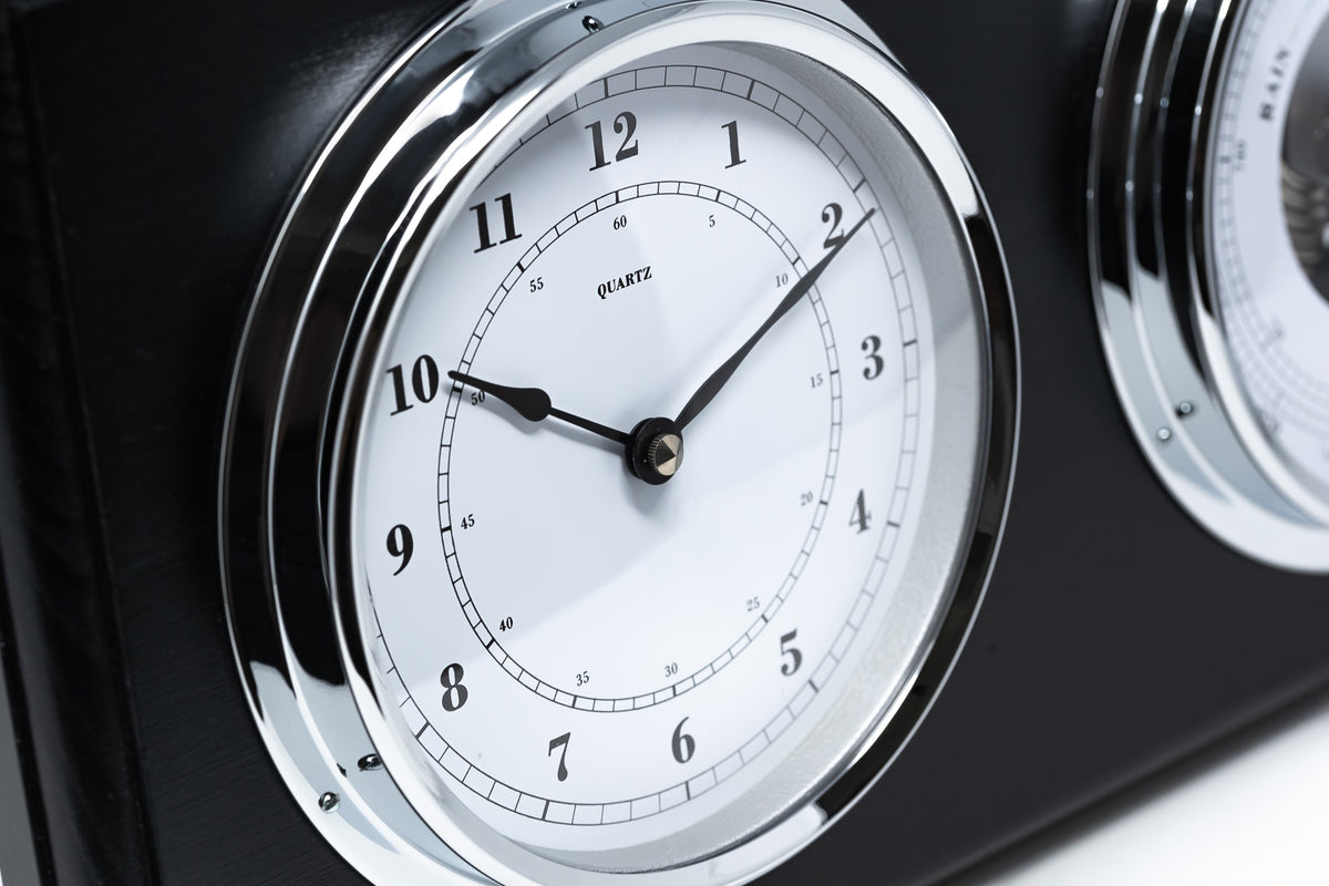 Close-up of a classic quartz clock with chrome bezel on a black weather station panel