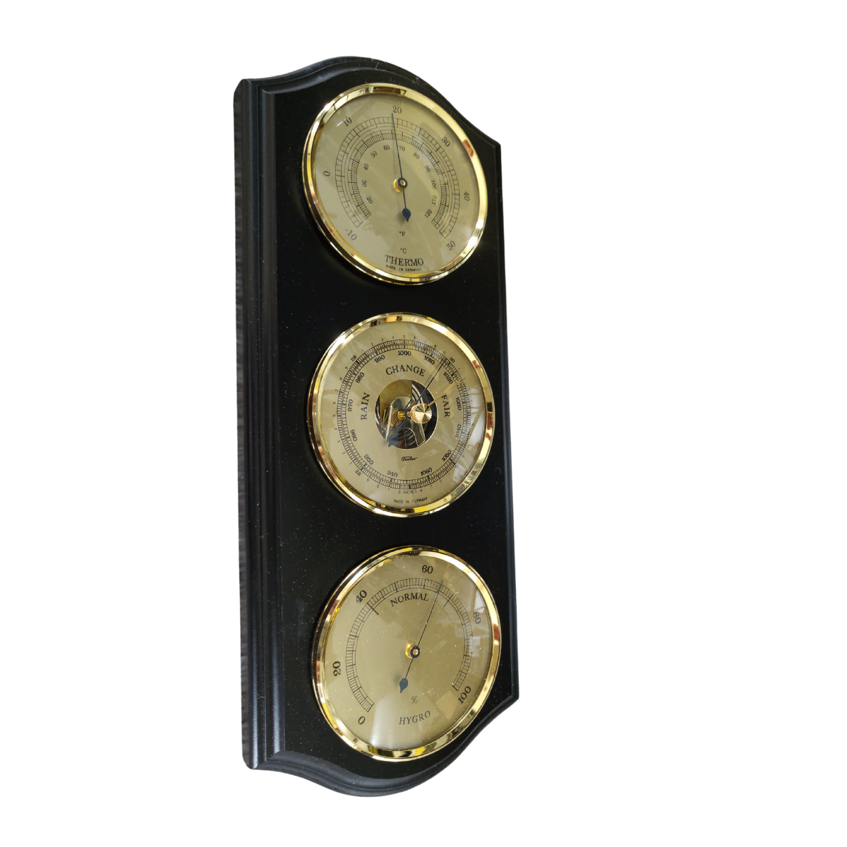 Wall-mounted brass weather station with barometer, thermometer, hygrometer in modern home interior.